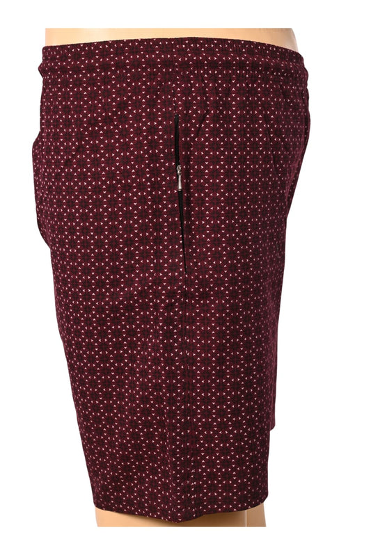 A front-facing professional ghost mannequin photograph of Blend men's deep maroon swim shorts with a geometric micro-pattern and an elastic waistband. The image highlights a secure zipper pocket on the right side profile and features the silver 'A BLEND' logo, set against a seamless white studio background. (Style: Ghost Mannequin)